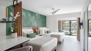 A modern hotel room with two beds, a dining table, and a balcony with a view.