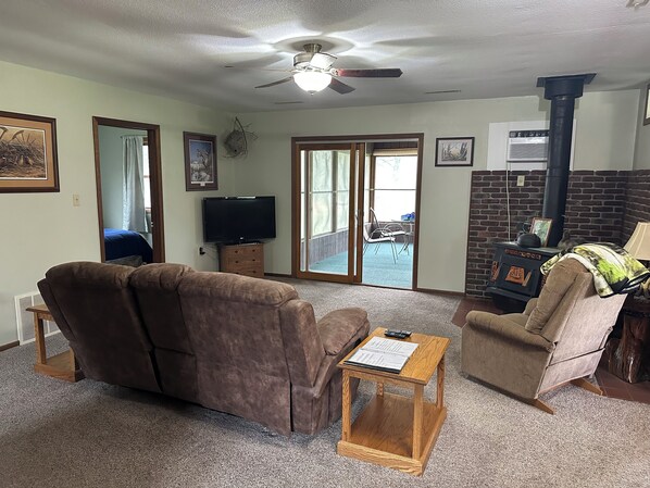 A living room with a sofa, armchair, TV, and a fireplace.