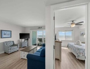 Una habitación con cama, escritorio, silla, televisión y vistas al exterior.