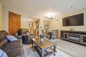 A living room with a sofa, coffee table, TV, and a dining area with chairs and a table.