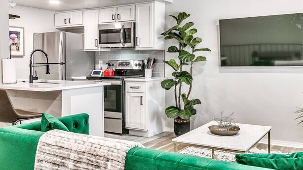 A modern kitchen with white cabinets, stainless steel appliances, and a central island.