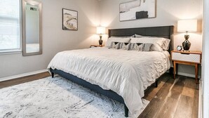 A bedroom with a bed, bedside tables, a ceiling fan, and artwork on the walls.
