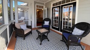 Een overdekt terras met rieten meubels, een patroon vloer en een plafondventilator.