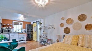 Et moderne hotelværelse med seng, skrivebord, stol, vaskemaskine og en væg med dekorative tallerkener.