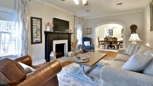 Ein Wohnzimmer mit Kamin, Ledersofas, Essbereich und Deckenventilator.