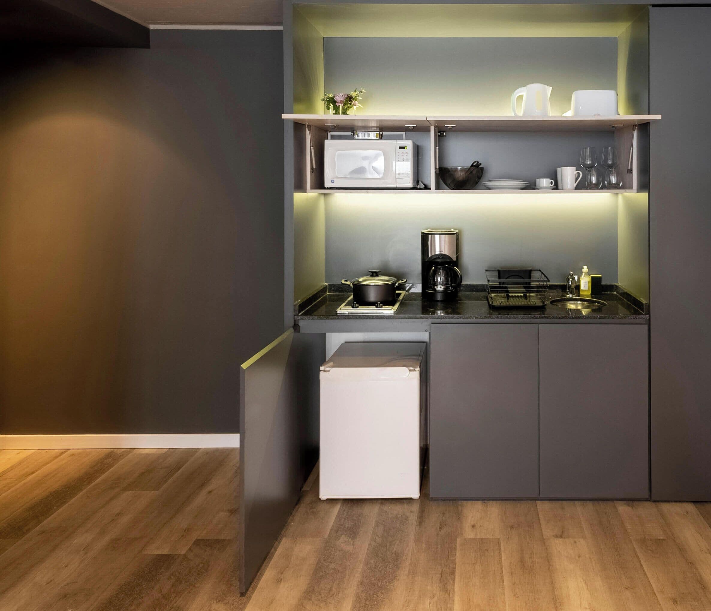A compact kitchen with a microwave, coffee maker, and a small refrigerator.