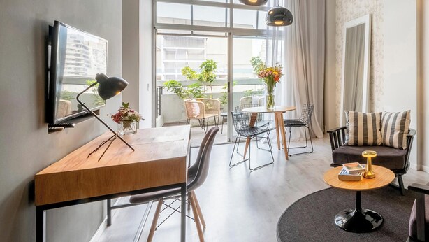 Un salon moderne comprenant un bureau, des chaises, un canapé, une table basse et un téléviseur.