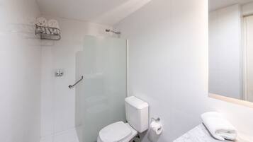 A modern bathroom with a glass shower enclosure, a toilet, and a marble sink with a towel.