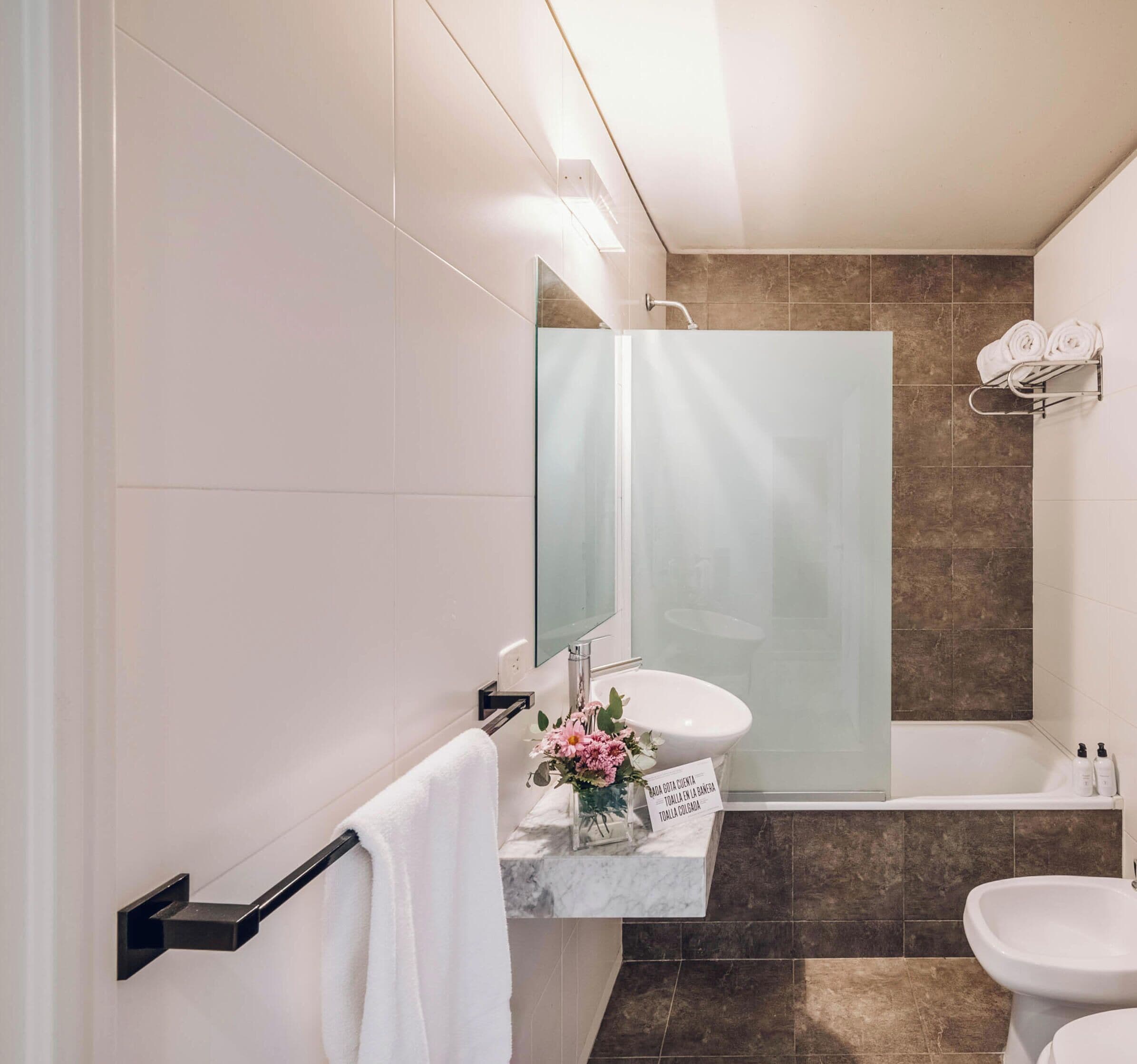 Un baño moderno con cabina de ducha de vidrio, un lavamanos blanco y un inodoro.