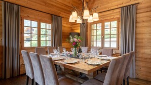 Comedor de madera con una mesa grande dispuesta para seis comensales, rodeada por seis sillas.