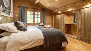 Un dormitorio de cabaña de madera con una cama, una ventana y un armario de madera.