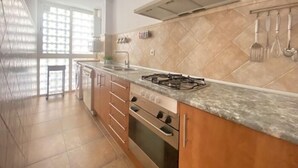 Une cuisine équipée d’une cuisinière à gaz, d’un four et d’une fenêtre avec des stores.
