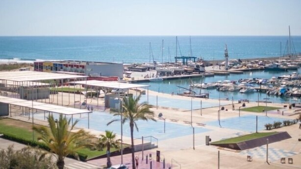 Un port de plaisance avec des bateaux amarrés, une piscine et un bâtiment doté d’un toit plat.