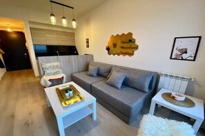 Ein modernes Wohnzimmer mit grauem Sofa, weißem Couchtisch und einem kleinen Beistelltisch mit Dekoration.