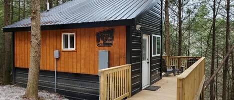 Una cabaña con fachada de madera, techo de metal y un balcón de madera.