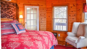 A cozy room with a bed, a chair, a door, and a window.