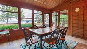 A dining area with a wooden table and chairs, large windows with a view of a lake and greenery. - Maya's Palace: Pet-Friendly Keuka Lake Escape! (Keuka Park)