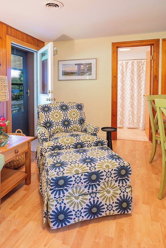 A room with a bed, a wooden desk, a chair, and a door leading outside.