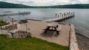 Un espace de pique-nique au bord du lac, avec un banc en bois et un muret en pierre.
