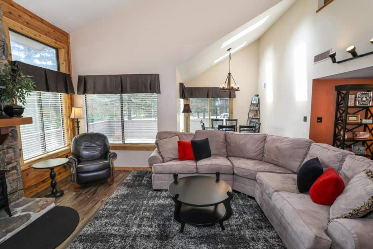 A cozy living room with a sectional sofa, a small round coffee table, a leather armchair, and a fireplace.