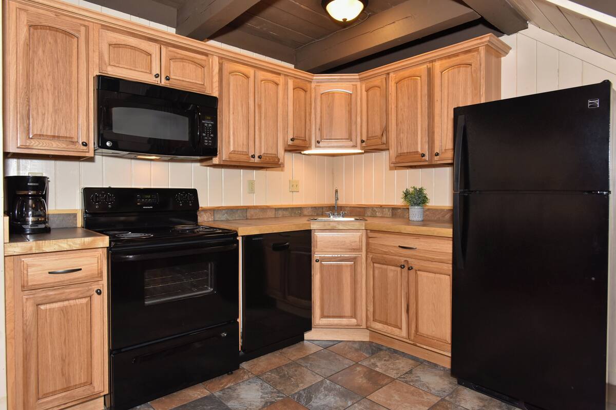 A kitchen with wooden cabinets, a black refrigerator, a microwave, a stove, and a dishwasher.