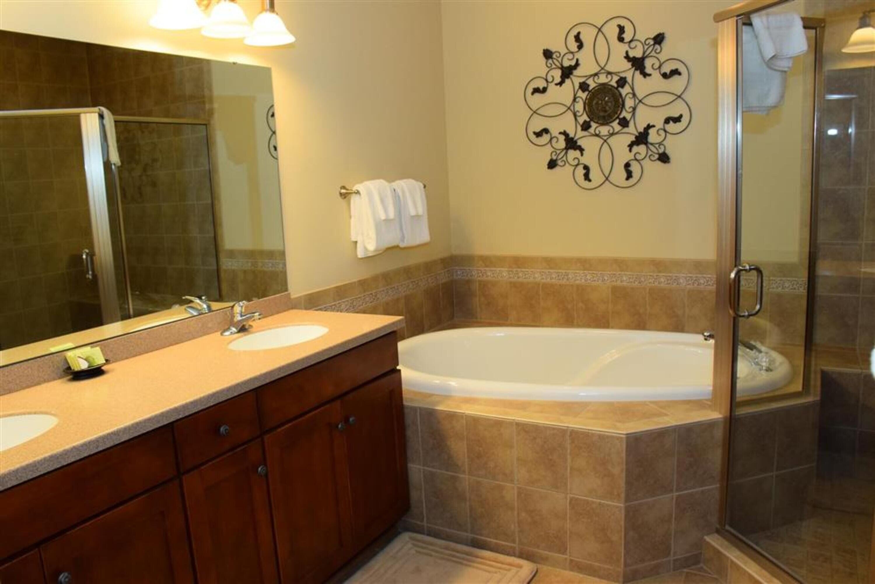 A bathroom with a double sink vanity, a large freestanding bathtub, and a glass shower enclosure.