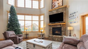 A spacious living room with a stone fireplace, a large TV, and a Christmas tree. - Seven Springs Resort  by Vail Resorts (Champion)