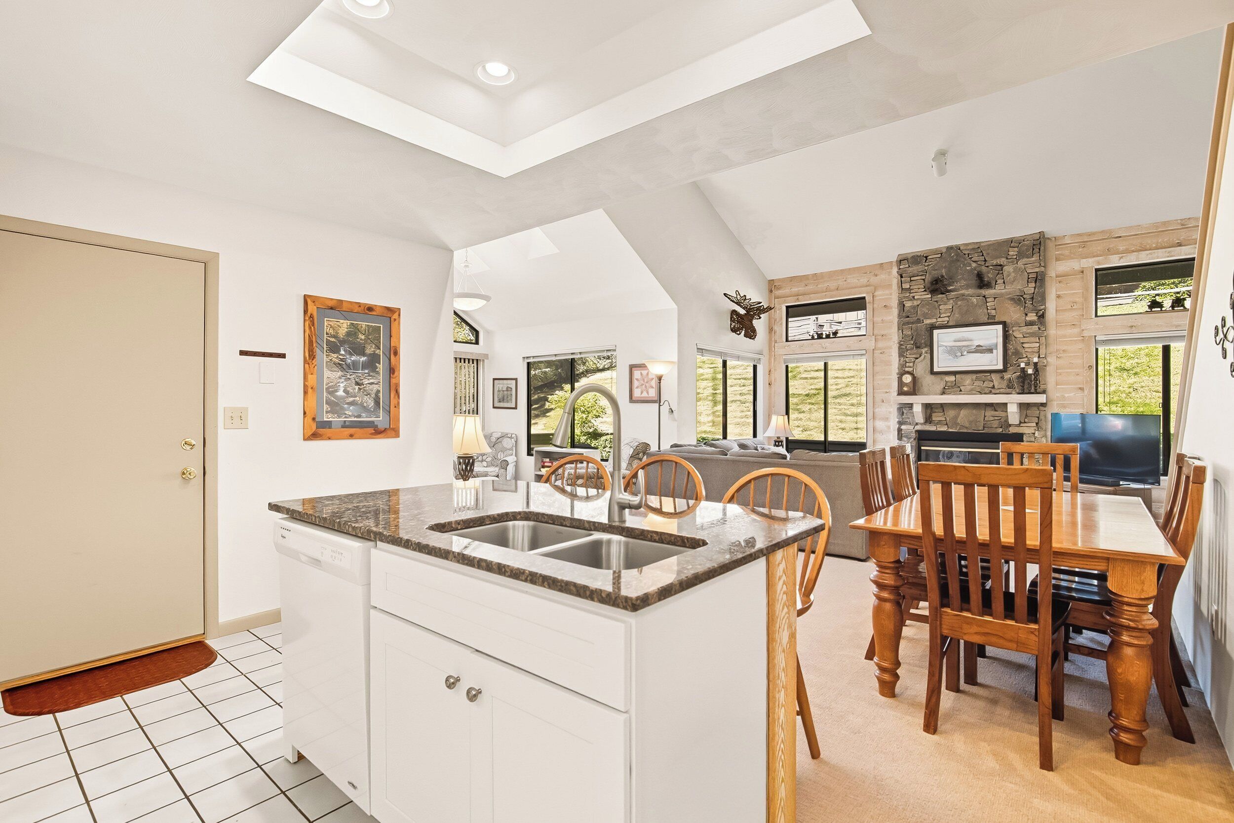 A kitchen with a central island, white cabinetry, and a dining area with wooden chairs and a table.