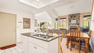 A kitchen with a central island, white cabinetry, and a dining area with wooden chairs and a table.