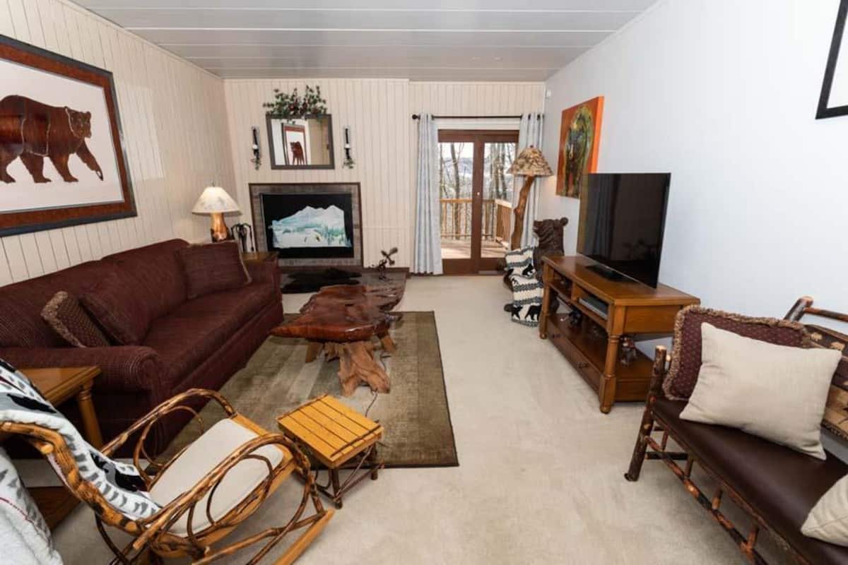 A cozy living room with a brown sofa, wooden coffee table, and wicker chairs.