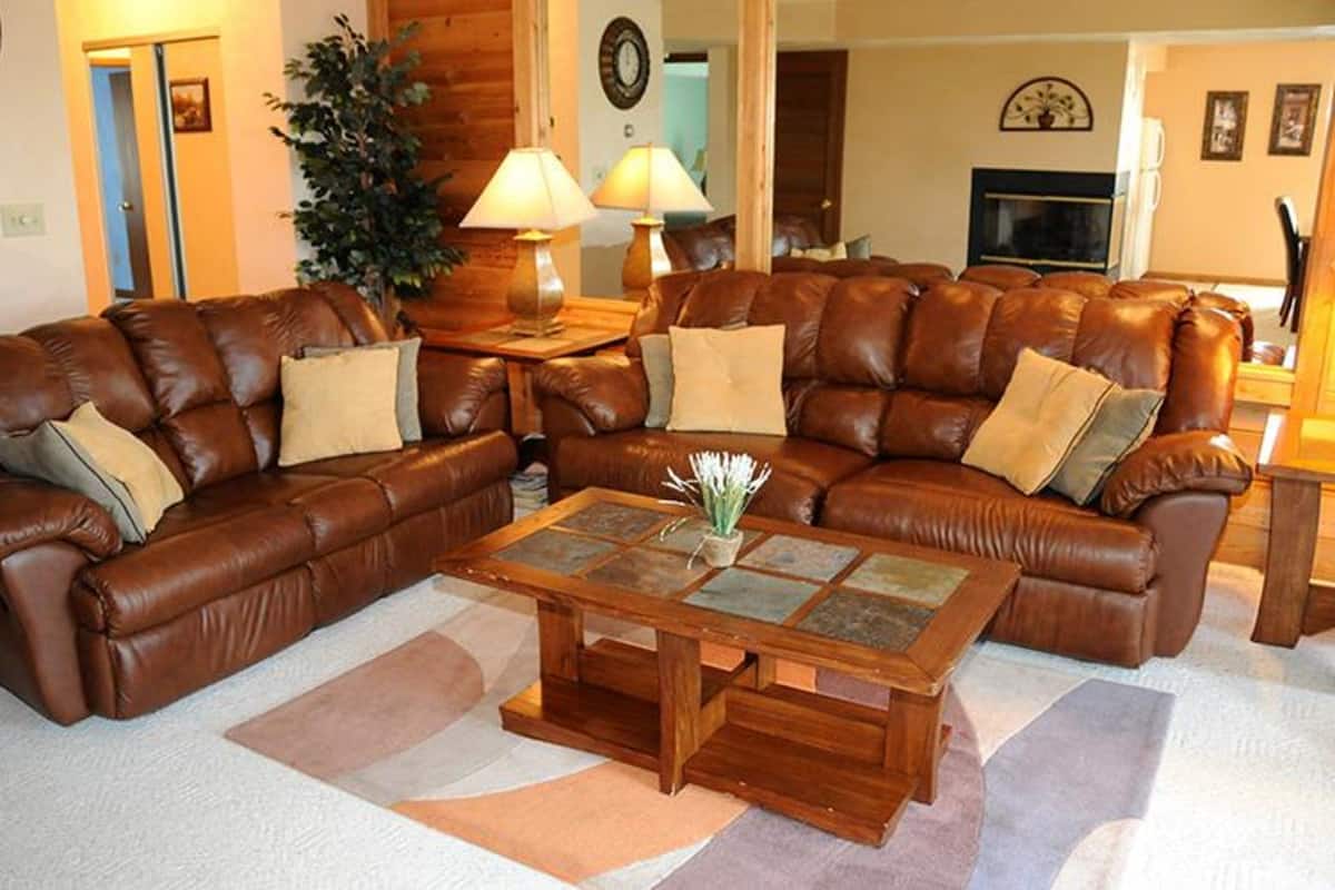 A living room with a brown leather sectional sofa, a wooden coffee table, and a potted plant.