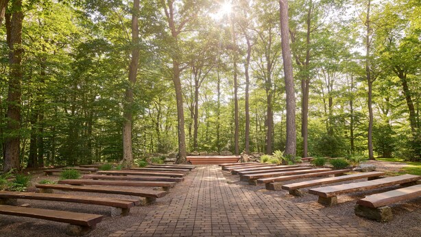 A forested area with a paved walkway and wooden benches. - Seven Springs Resort  by Vail Resorts (Champion)