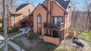 A modern two-story house with a balcony, a covered porch, and a small front yard with a pathway. - Seven Springs Resort  by Vail Resorts (Champion)