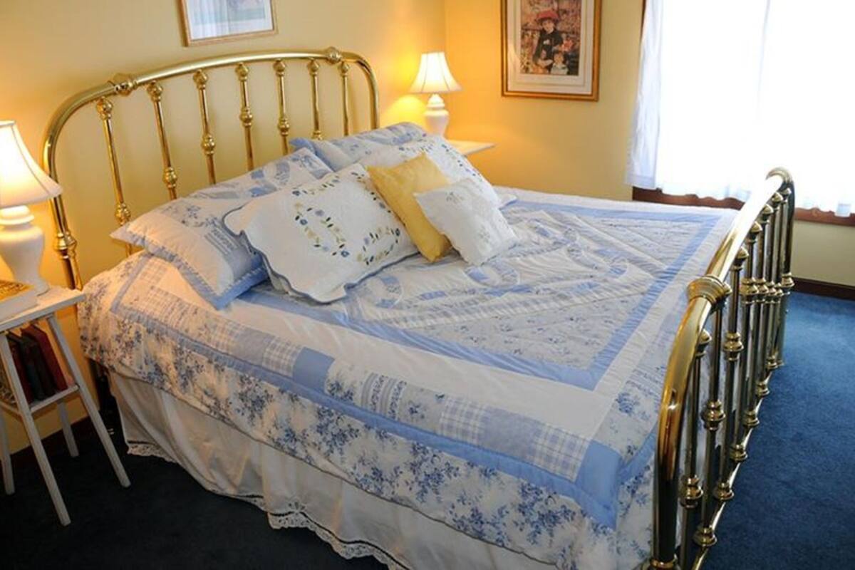 A bed with a floral bedspread, two bedside lamps, and a framed picture on the wall.