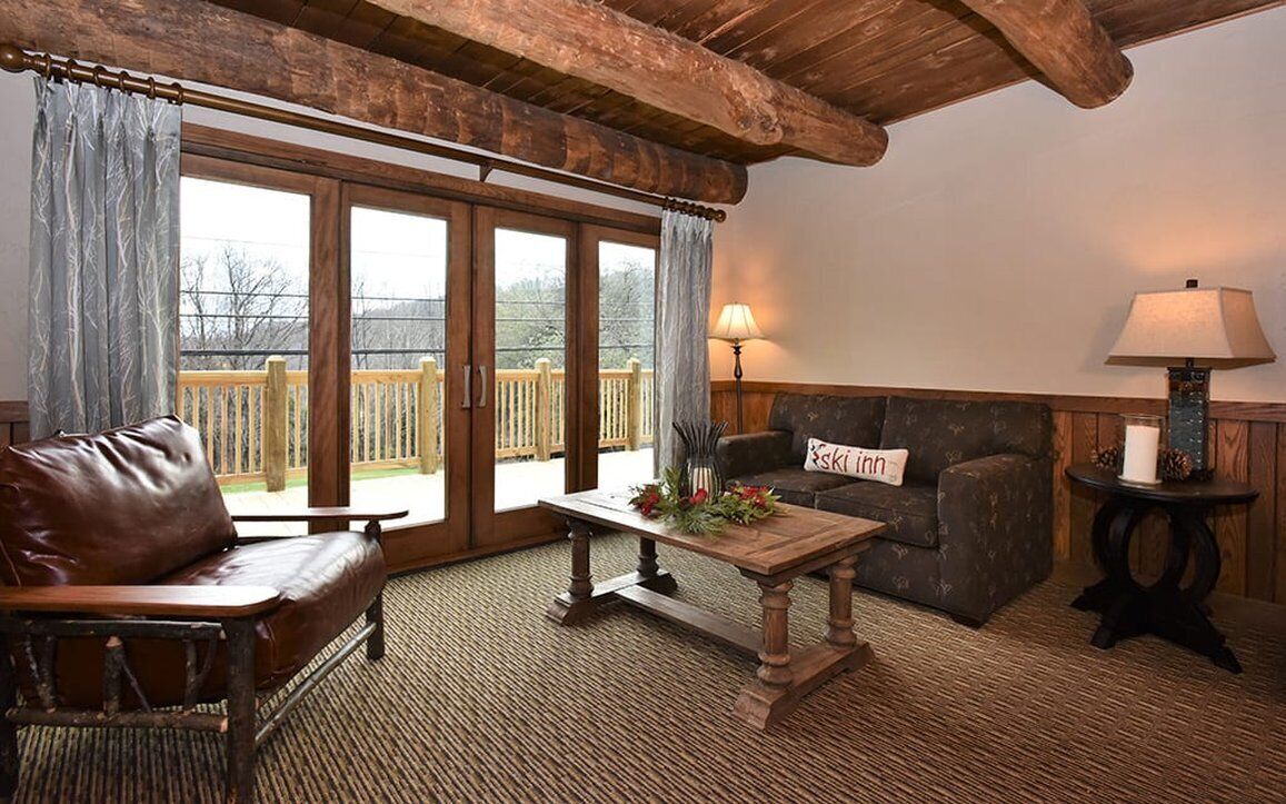 A cozy room with a leather sofa, a wooden table with a vase, and a lamp.