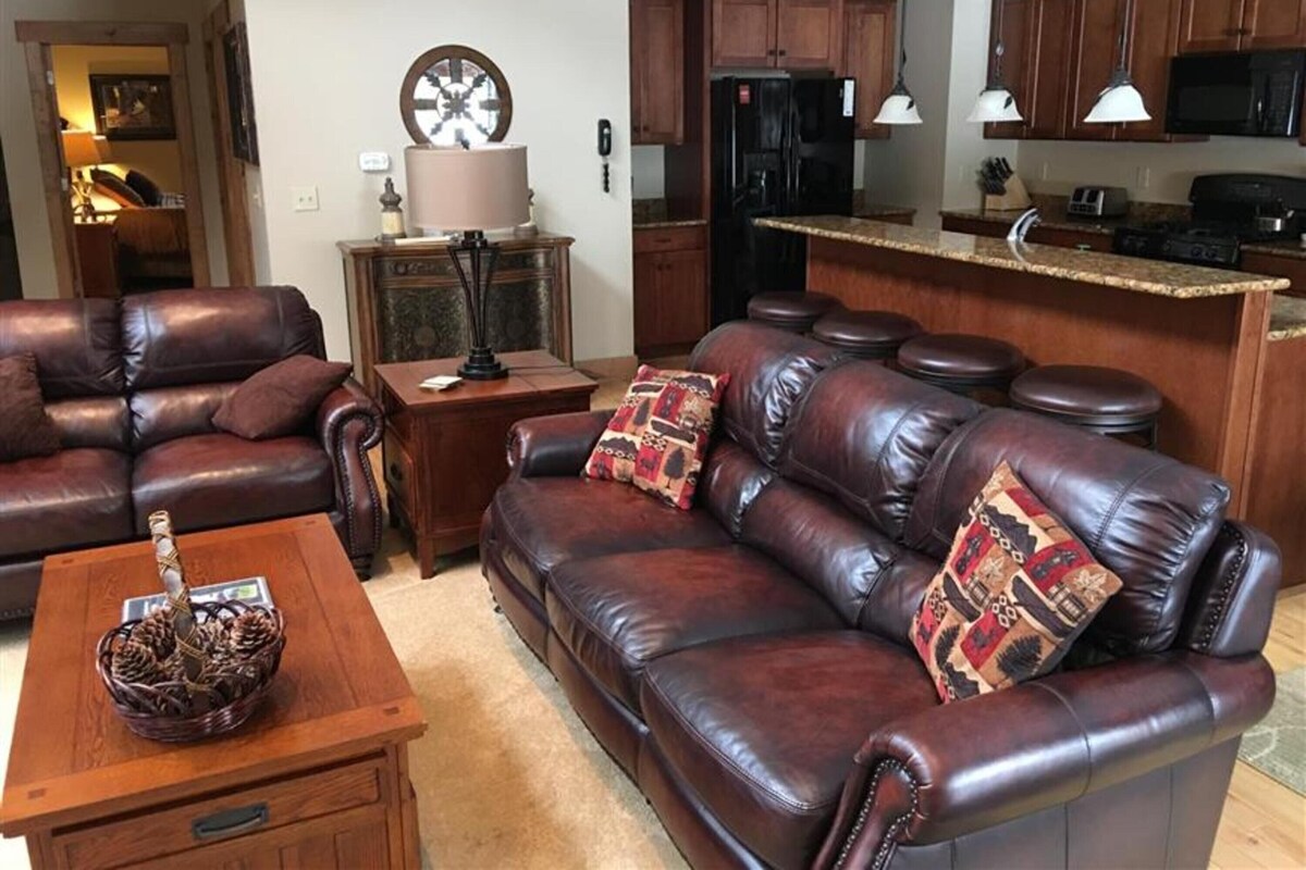 A living room with a brown leather sofa, a wooden coffee table, and a decorative lamp.