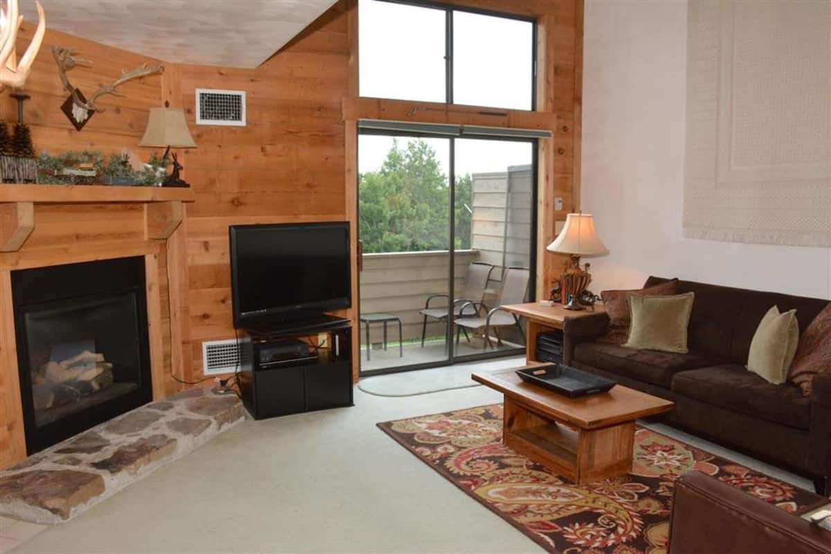A cozy living room with a fireplace, a television, a sofa, and a dining area with a table and chairs.