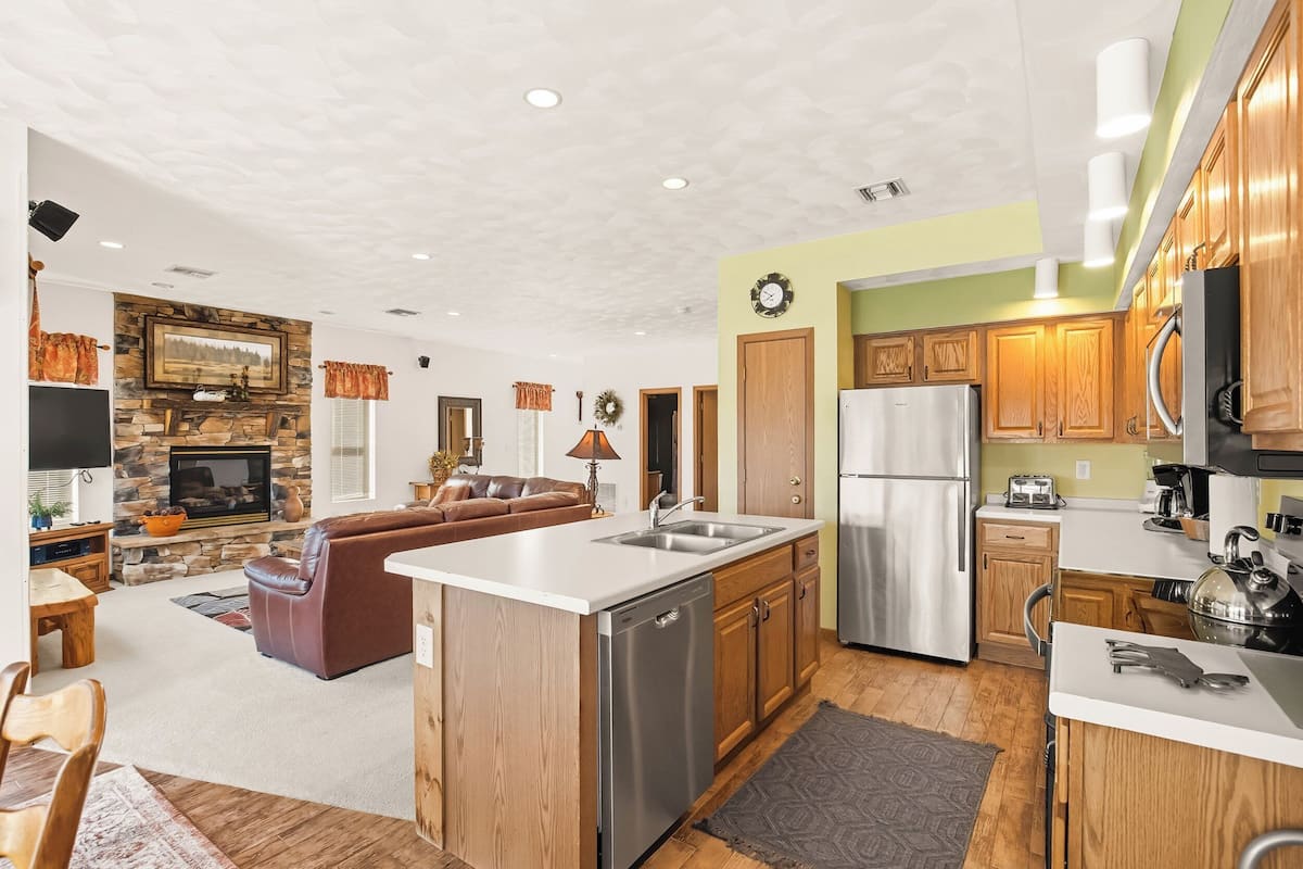 A modern kitchen with a central island, wooden cabinets, and stainless steel appliances.