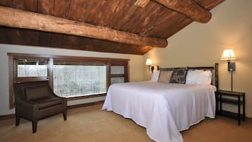 A bedroom with a large bed, a chair, and two wall-mounted lamps.