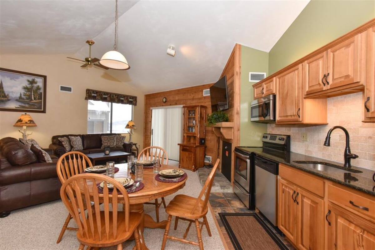 A compact kitchen with wooden cabinets, a microwave, and a dishwasher.