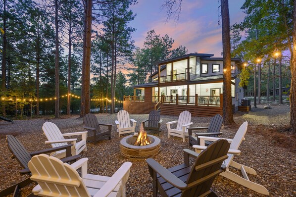 Eine Lodge mit Feuerstelle und Adirondack-Stühlen in einer Waldlandschaft.