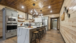 Une cuisine moderne avec des murs en bois, des appareils électroménagers en acier inoxydable et un îlot en marbre agrémenté de tabourets de bar.