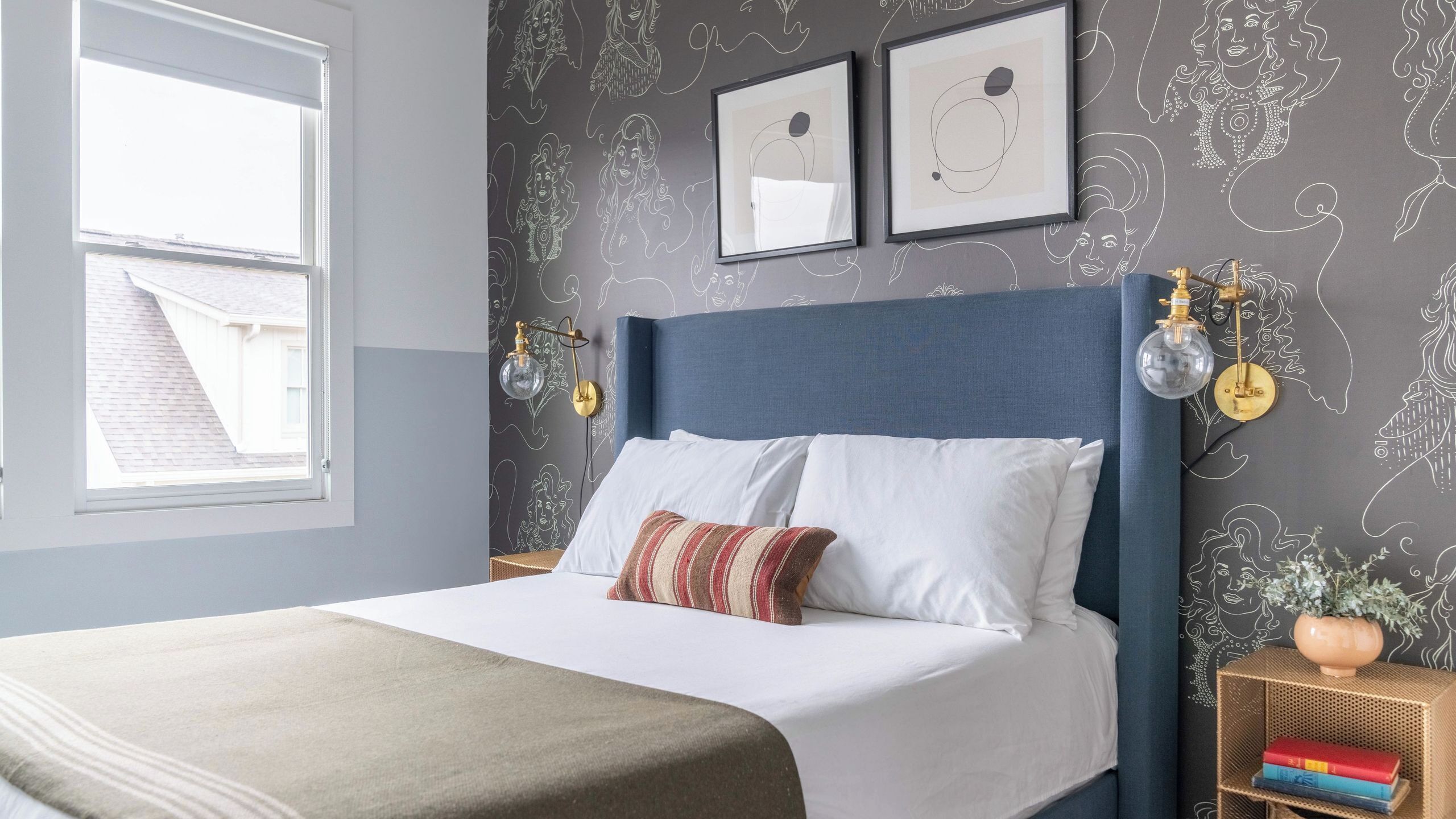 Un dormitorio con cama, ropa de cama blanca, cabecera azul y decoración en la pared.