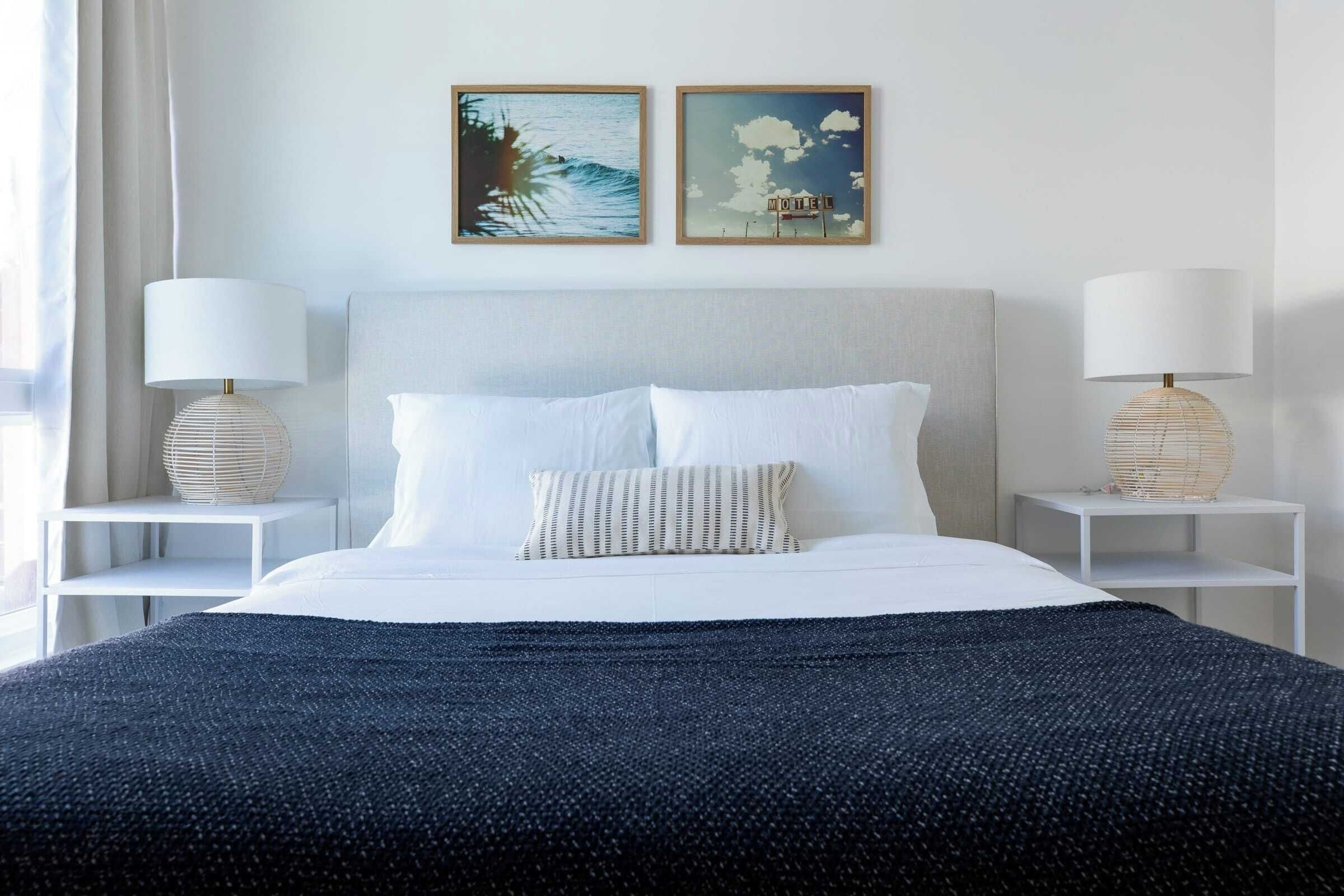 A neatly arranged hotel room with a large bed, two bedside tables with lamps, and two framed pictures on the wall.