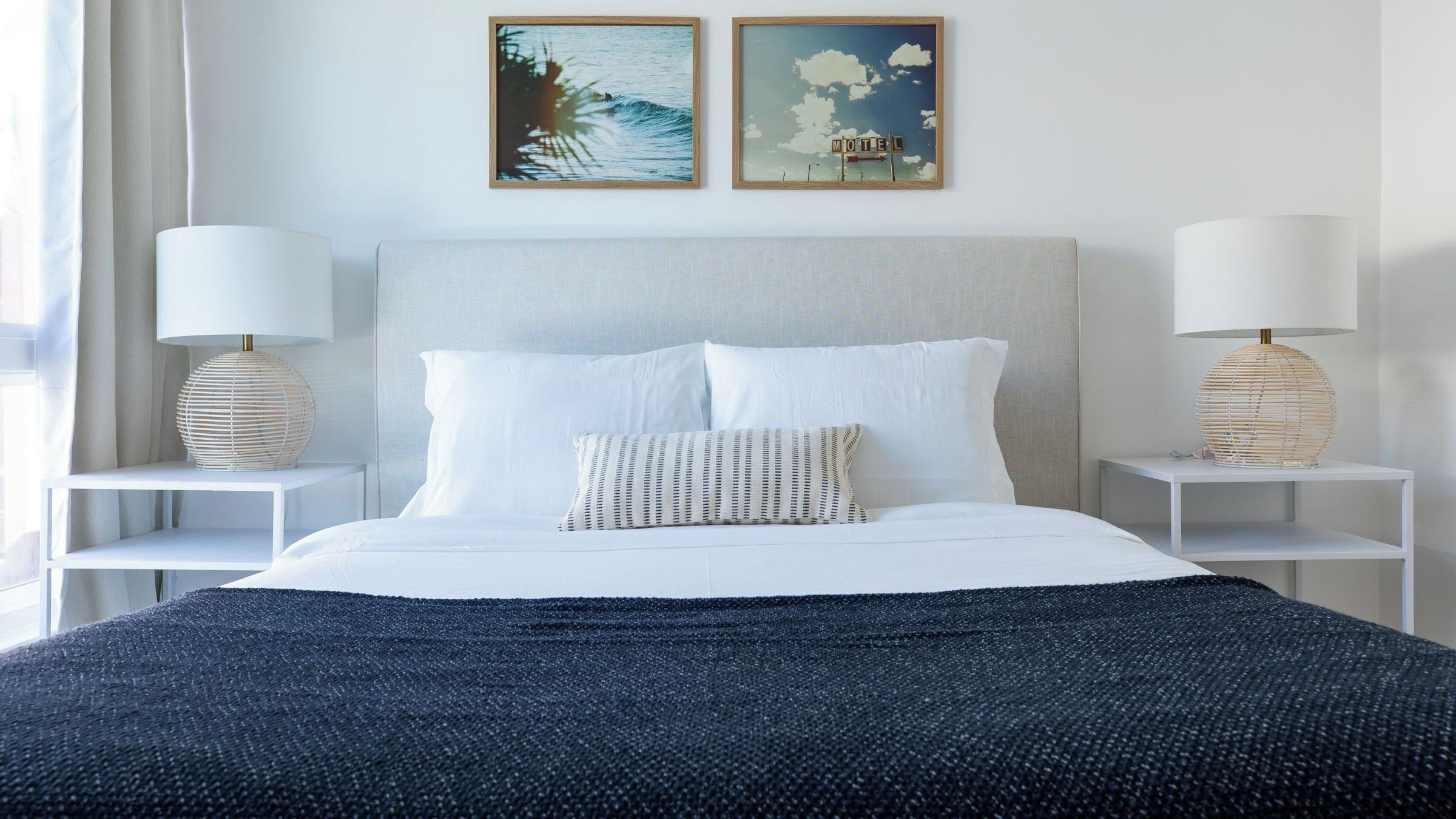 A neatly arranged hotel room with a large bed, two bedside tables, and two wall-mounted paintings.