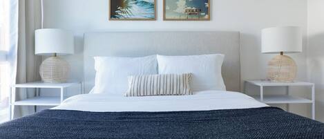 A neatly arranged hotel room with a large bed, two bedside tables, and two wall-mounted paintings.