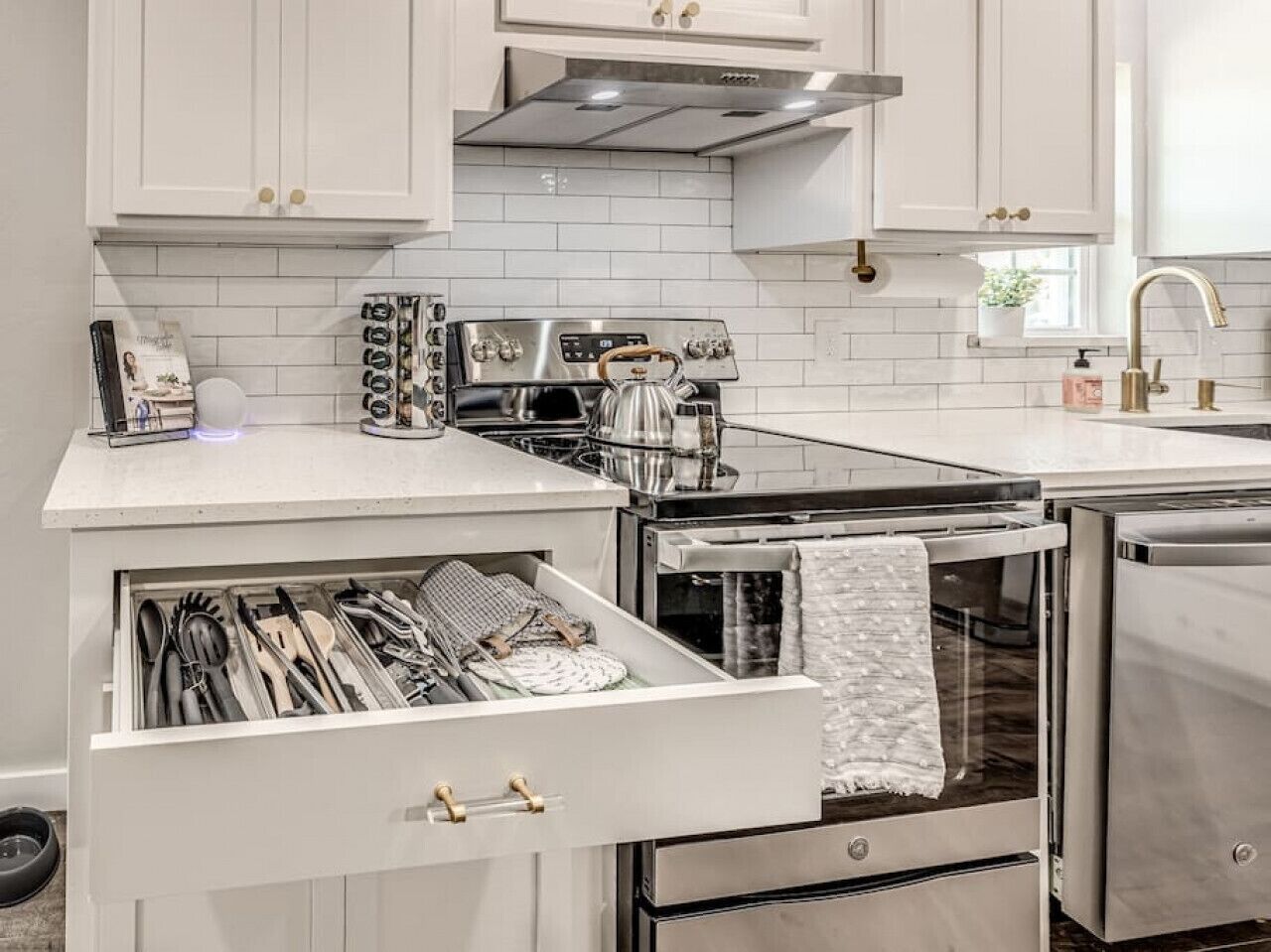 A modern kitchen with white cabinetry, stainless steel appliances, and a built-in oven.