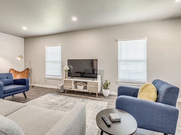 A modern living room with a flat-screen TV, two sofas, a coffee table, and a sideboard.