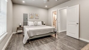 Un dormitorio con cama, mesitas de noche, ventilador de techo y una puerta.