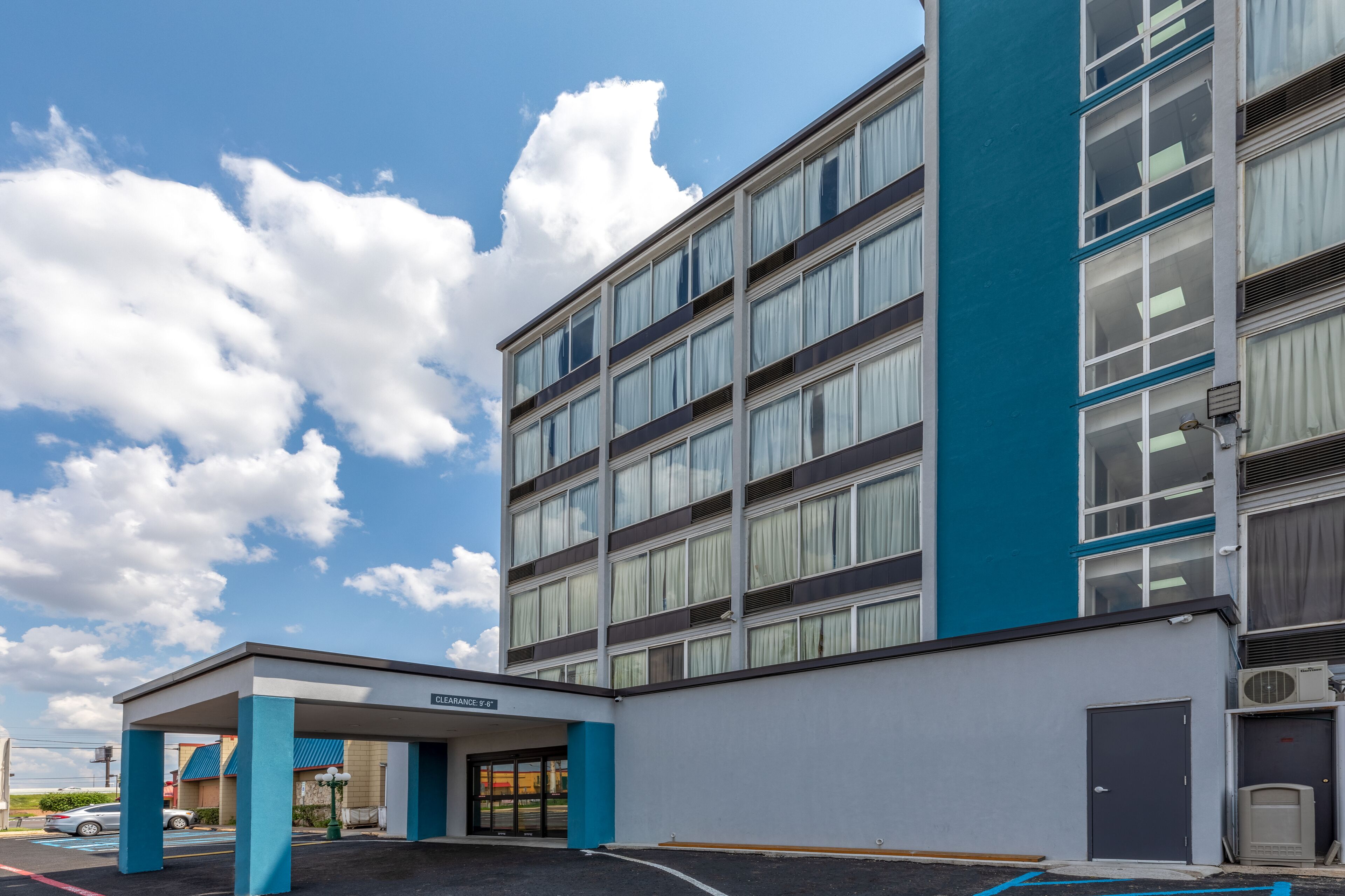 A multi-story hotel with a covered entrance and a parking area.